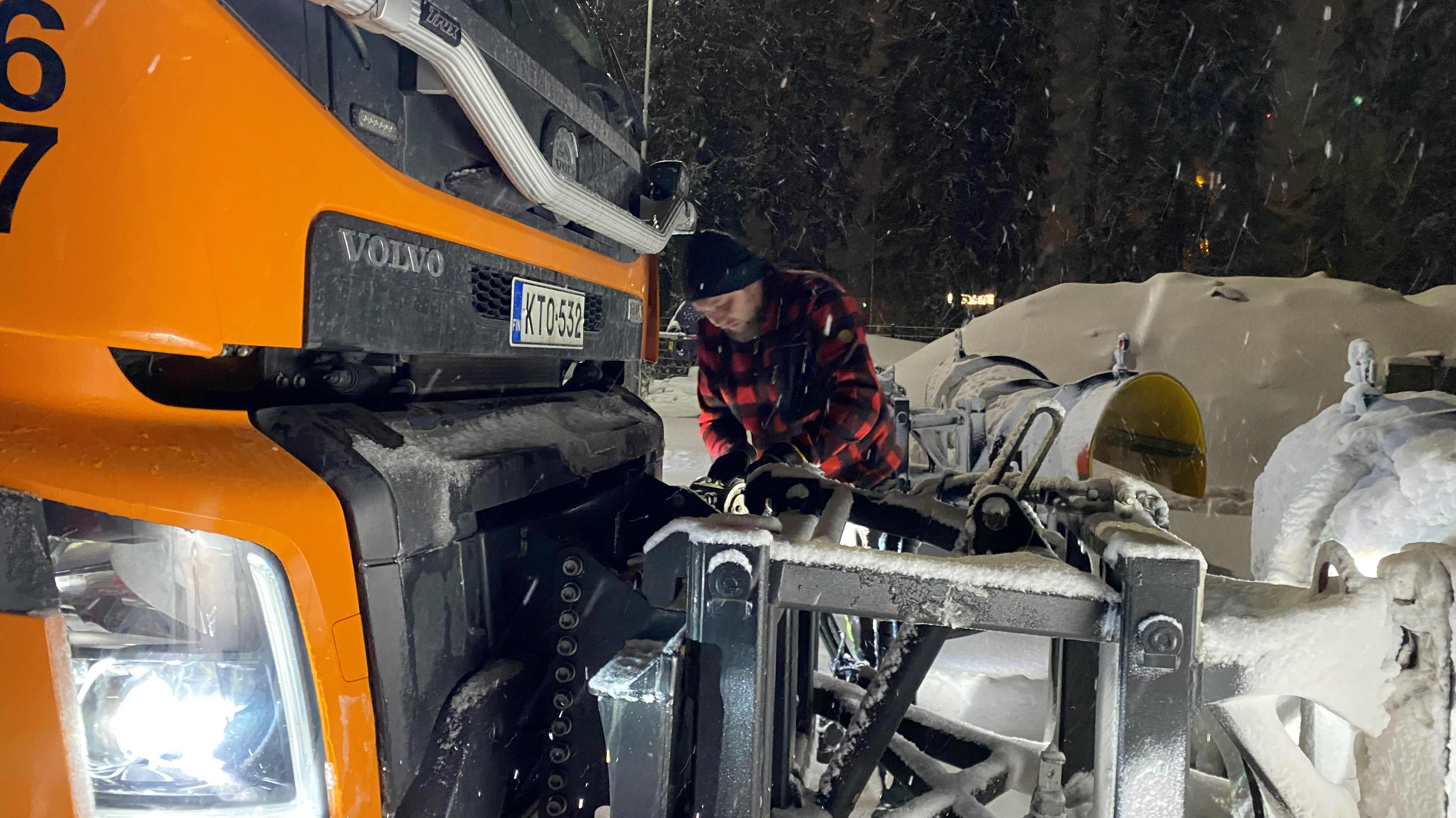 Riihimäen kaupungin kunnossapidon työntekijä Toni Kokkonen asentaa auraa kuorma-auton nokkaan lumisateessa pimeänä aamuna.