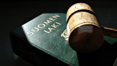 A judge's gavel on top of a Finnish law book with a green cover.