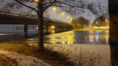 Vesi virtaa sulana sillan alla tammikuussa iltahämärällä.