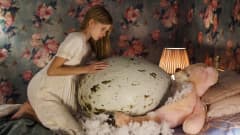 Tyttö istuu sängyllä ja tunnustelee edessään olevaa valtavan suurta linnunmunaa.