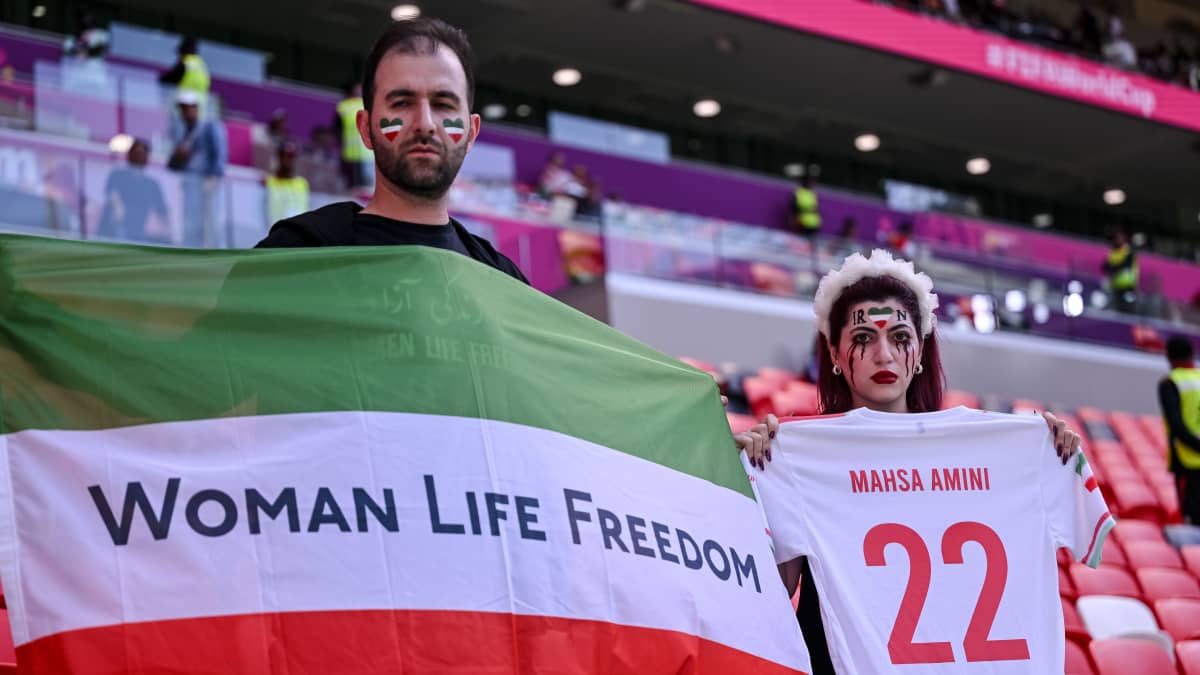 Mies ja nainen osoittivat mieltään Iranin hallintoa vastaan jalkapallon MM-kisojen katsomossa.