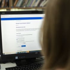 Lidia Backlund, a student from Joensuu, Finland, browsing the Kela housing allowance website. The picture shows the back of her head and the computer screen. 