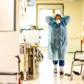 Sairaanhoitaja pukeutumassa suojavarusteisiin ennen koronapotilaan luokse menemistä.