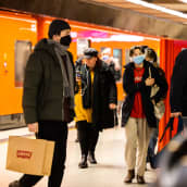 Ihmisiä metroasemalla kasvomaskeihin suojautuneena.