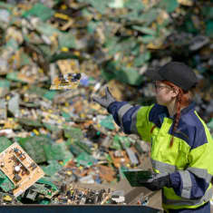 Kuusankoski Oy:n työntekijä heittää elektroniikkajätettä jätekasaan.