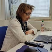 Simulaationäyttelijä Sinikka Myllyoja istuu tietokoneen ääressä näyttelijän roolissa.