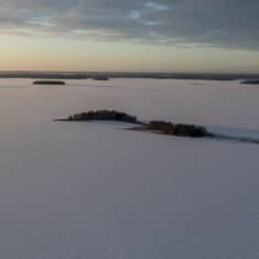 Talvinen Lappajärvi ilmasta kuvattuna. Pieniä saaria ja aurinko laskemassa.