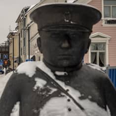 Ihmisiä kävelee Oulun Toripoliisin patsaan takana