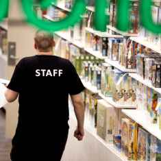 Kaupan työntekijä staff paita yllään kävelee kaupassa.