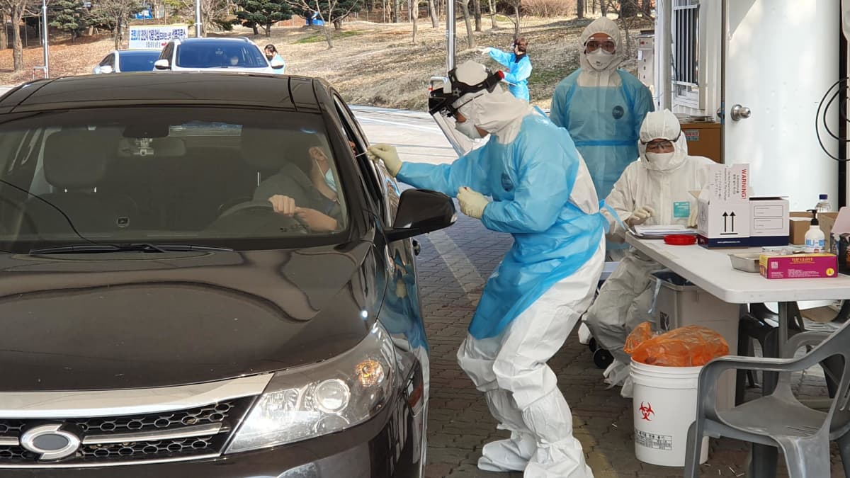 Terveydenhuollon työntekijä ottaa koronavirustestiä autonsa ikkunan avanneelta henkilöltä Cheonanissa Etelä-Koreassa 29. helmikuuta 2020.