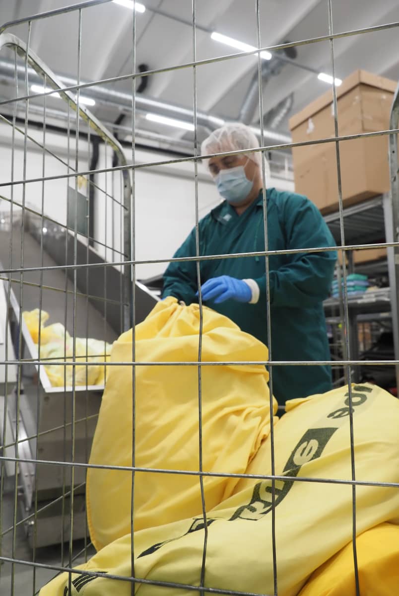 Työntekijä avaa pyykkipussia Sakupen pesulassa Joensuussa.