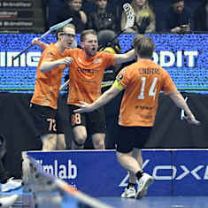 Oranssipaitaiset salibandynpelaajat tuulettavat maalia.