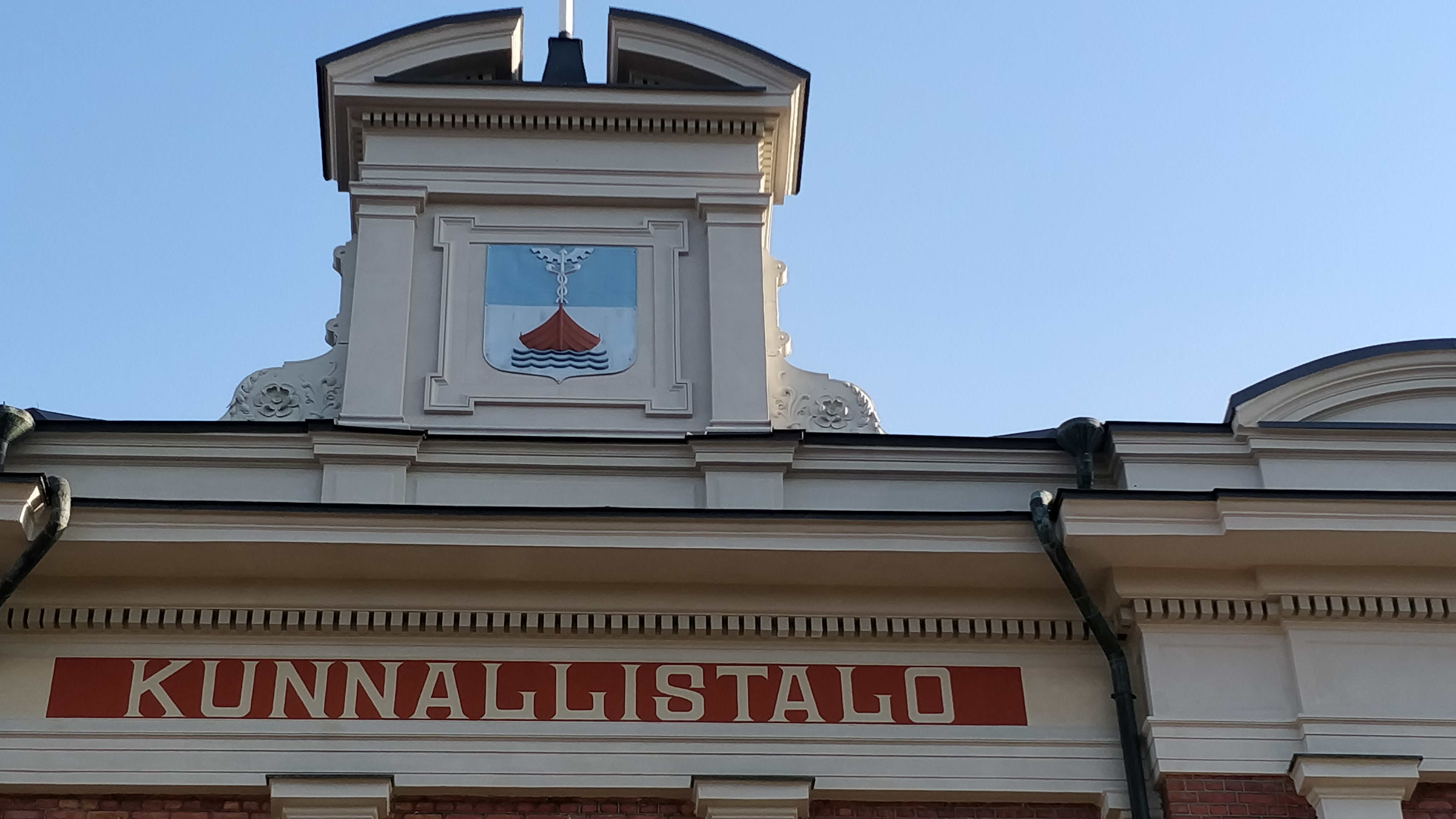 Yksityiskohta Jyväskylän kaupungintalon ulkoseinän yläreunasta, jossa lukee teksti Kunnallistalo. Katolla on myös uloke, jossa on Jyväskylän kaupungin vaakuna.