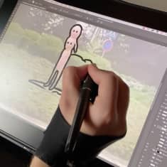 Käsi piirtää tietokoneruudulle kaksipäistä hahmoa jonka taustalla näkyy puisto.