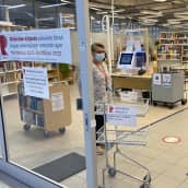 Kauppakeskuksessa väistötiloissa oleva Riihimäen kirjaston ovensuu. Avoimesta ovesta näkyy virkailija ja kirjahyllyjä.