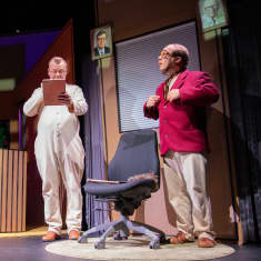Kemin teatterin Fingerpori-näytelmän kohtaus, jossa kaksi miestä etualalla ja kaksi laulavaa naishahmoa taustalla.