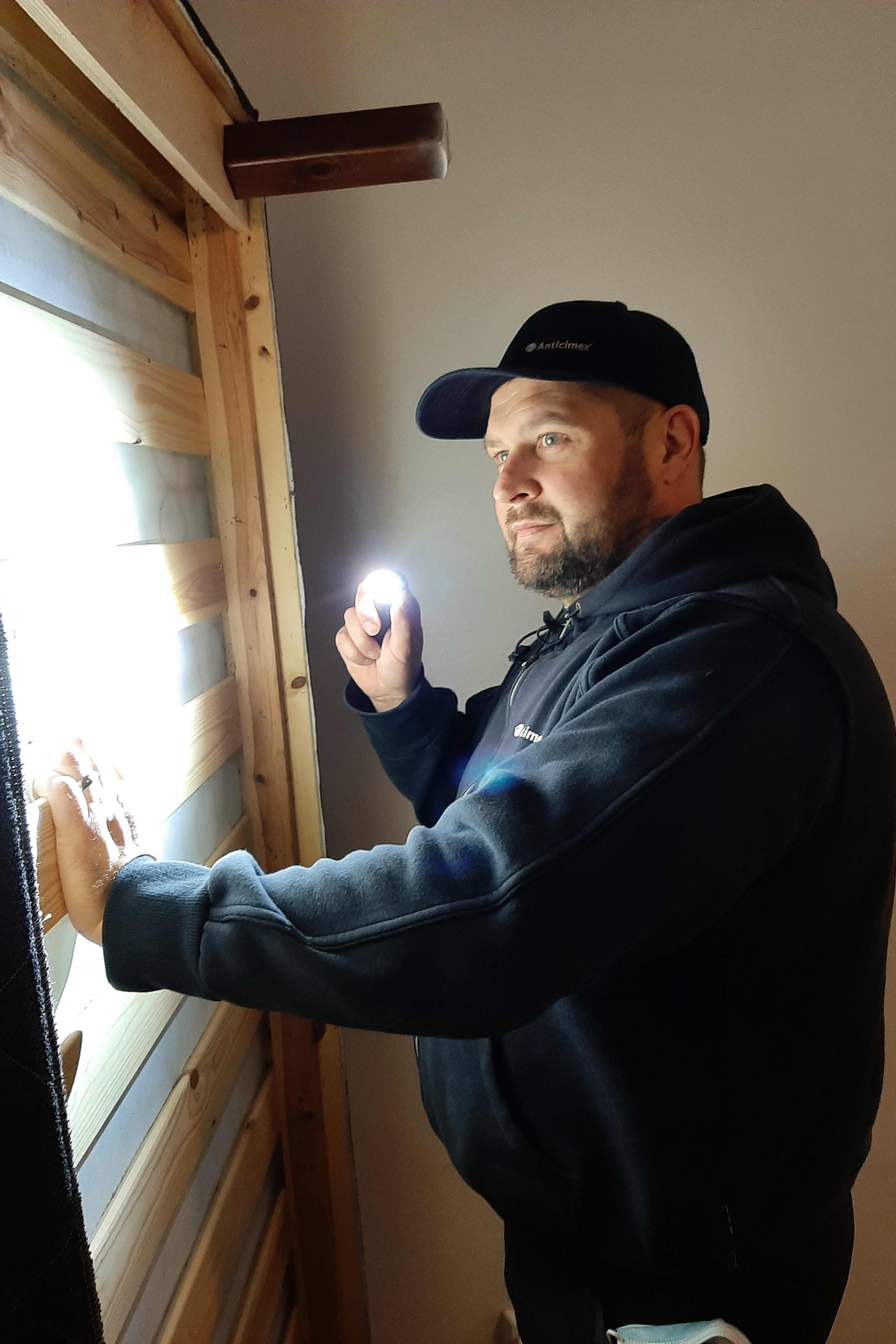 Pasi Pentilä tutkii pystyyn nostettua sängynrunkoa ja hänellä on kädessään taskulamppu