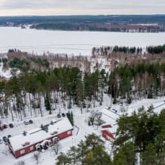 Piispalan rakennuksia ja järvimaisema taka-alalla.