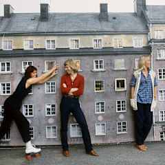 Abba spexar framför en liten kuliss av ett höghus.