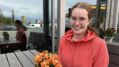 Hymyilevä Helmiina Sairberg istuu ulkona pöydän ääressä ja katselee eteenpäin. Pöydillä on kukkia.