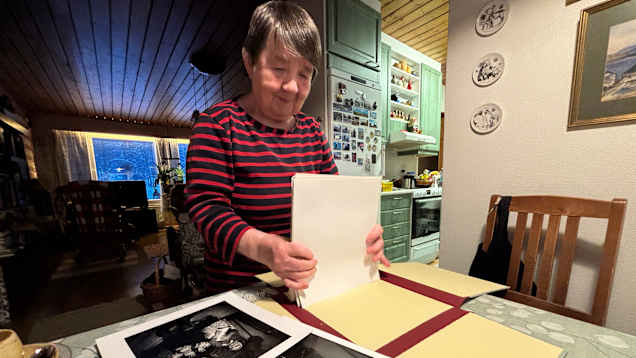Nainen järjestelee vanhoja valokuvia käsissään. Irja Jefremoff. 