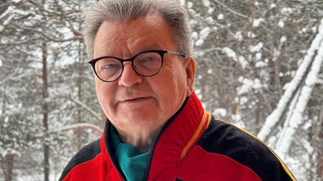 Veli-Pekka Lehtola katsoo suoraan kameraan Sajoksen takapihalla Inarissa, taustalla laavupuut.