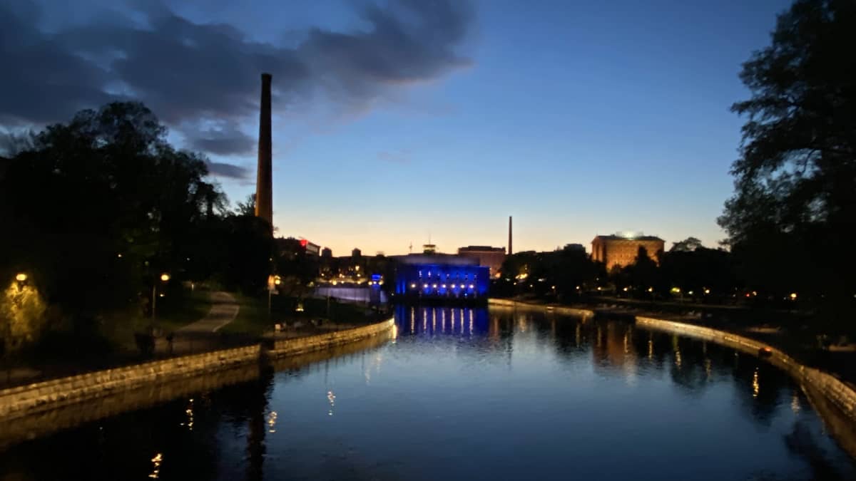 Tampereen Tammerkoski yöllä. Taivas on sininen ja heijastuu veden pinnasta. Rakennukset on valaistu siniseksi.