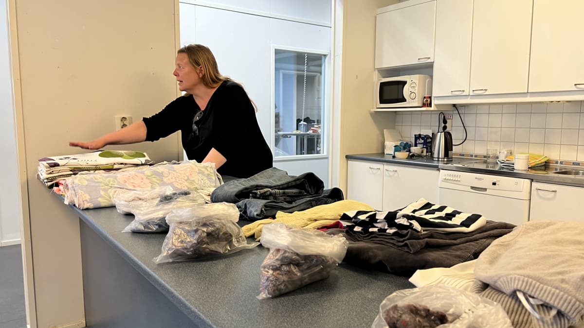 Mari Juntunen esittelee tekstiilejä, jotka on levitetty pöydälle. 