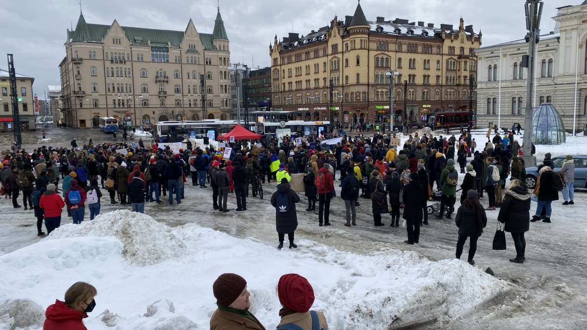 Mielenosoittajia Tampereen keskustorilla. Kuva kaukaa ihmisjoukosta, taustalla näkyy Hämeenkatu. Torilla on paljon lunta. 