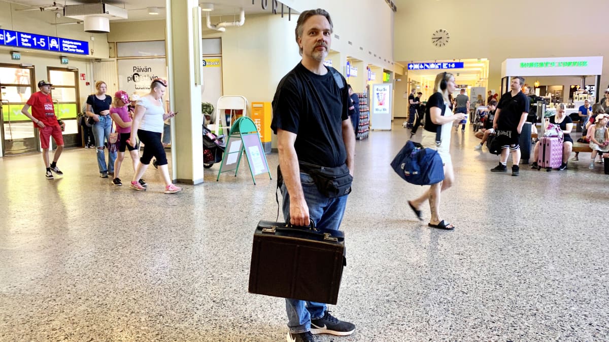 Heikki Saha seisoo laukun kanssa Tampereen rautatieasemalla.
