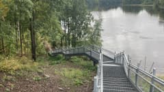 Maisemaa joen varrella, metallinen siltarakennelma kävelijöille.
