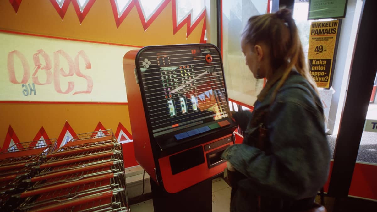 Nainen pelaa raha-automaattipeliä valintamyymälän eteisessä vuonna 1990.