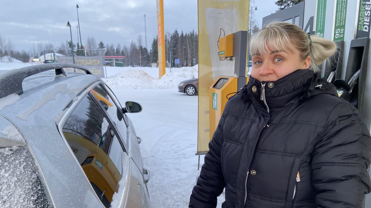 Anu Nousiainen Juvan ABC:llä henkilökuvassa. Vieressä hänen autonsa ja takana bensatankki.