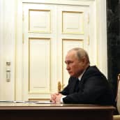 Vladimir Putin istuu työpöydän takana sivuprofiilissa.