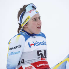 Ebba Andersson istuu maassa hiihtokilpailun jälkeen.