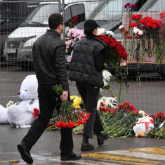 Ihmiset tuovat kukkia Moskovassa Crocus City Hall -konserttitalon parkkipaikalle terrori-iskun takia 23.3.2024.