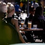 Anonyymi ihminen juo kahvia aurinkoisella terassilla. 