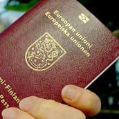 Suomen passin kansilehti ihmisen kädessä.