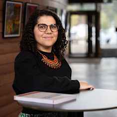 Bianca Benini-Morottaja katsoo kameraan ja hymyilee Saamelaiskulttuurikeskus Sajoksessa. 