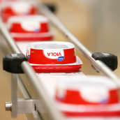 Sulatejuustopaketteja tehtaan liukuhihnalla.