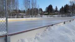 Autio jääkiekkokaukalo talvisessa maisemassa.