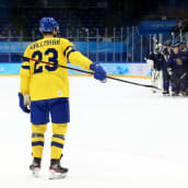 Linus Wallmark katsoo juhlivaa Suomen joukkuetta jääkiekkokaukalossa.