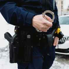 Photo shows an unidentified police officer holding a set of handcuffs.
