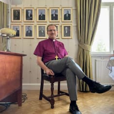 Oulun hiippakunnan piispa Jukka Keskitalo istuu työhuoneessaan entisten piispojen valokuvien edessä.