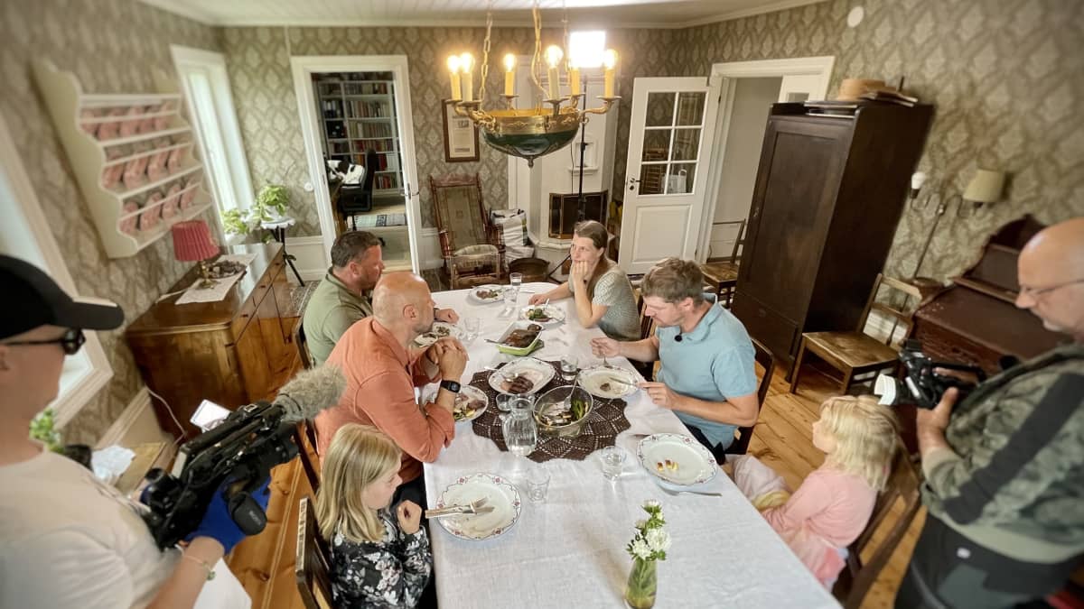 Personer sitter kring ett matbord och äter.