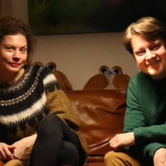 Viulistipariskunta Minna Pensola ja Antti Tikkanen istuvat vierekkäin kotinsa sohvalla ja katsovat kameraan hymyillen. 
