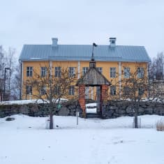 En gul gammal prästgård i vinterlandskap. 
