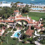 En enorm lyxvilla med pool och palmer överallt. I övre kanten skymtar havet.