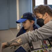 Isä ja poika kirjastossa, kirjoja kädessä.