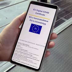 EU:n koronatodistus-teksti näkyy kädessä olevan kännykän näytöllä.
